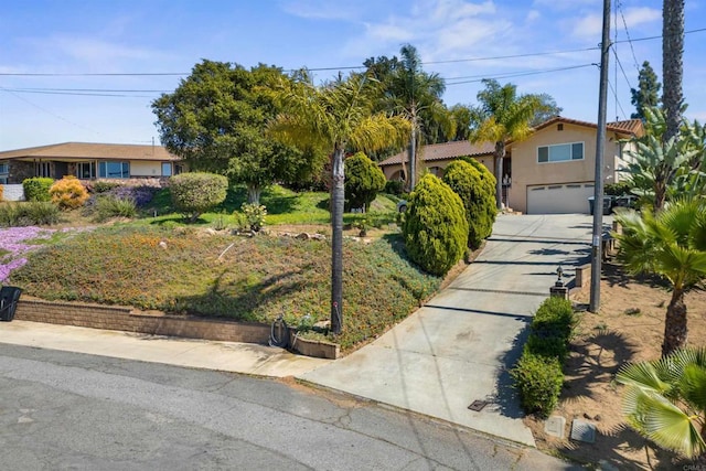 view of front facade with a tiled roof, driveway, stucco siding, and an attached garage
