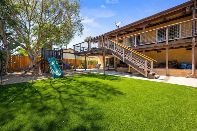 back of house with a patio, a lawn, stairway, fence, and a playground