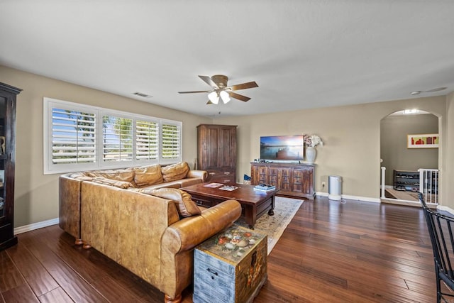 living area with arched walkways, visible vents, hardwood / wood-style flooring, and a ceiling fan