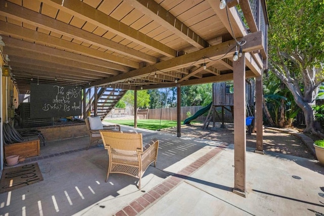 view of patio featuring a playground, fence, and stairs