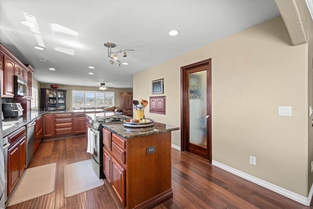 kitchen with dark wood-type flooring, baseboards, appliances with stainless steel finishes, and recessed lighting
