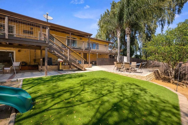 back of house featuring a deck, a yard, fence, stairway, and a patio