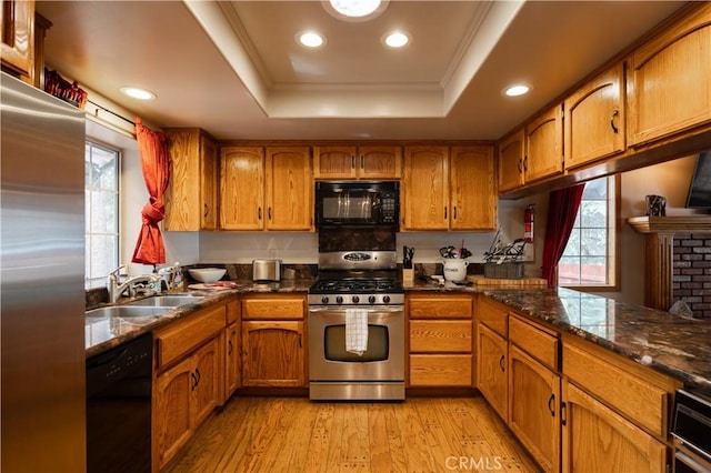 kitchen with brown cabinets, a sink, a raised ceiling, and black appliances
