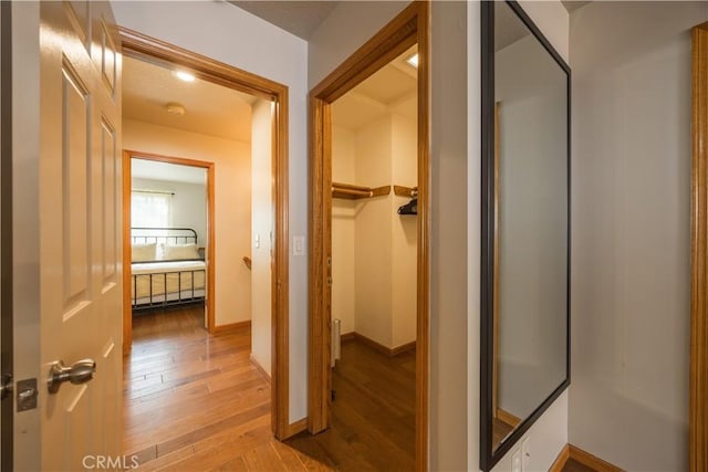 corridor featuring light wood-style floors and baseboards