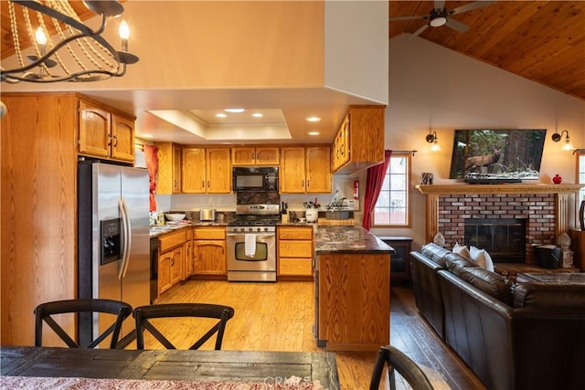 kitchen featuring dark countertops, light wood-style floors, black appliances, brown cabinetry, and open floor plan