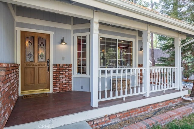 view of exterior entry with brick siding and covered porch