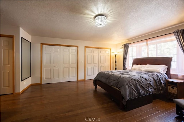 bedroom featuring hardwood / wood-style flooring, a textured ceiling, and two closets