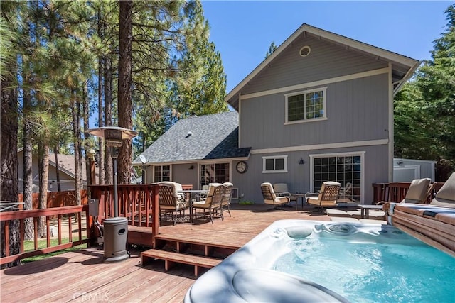 back of house with a covered hot tub, outdoor dining area, roof with shingles, and a deck