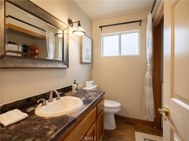 full bath featuring wood finished floors, visible vents, toilet, vanity, and baseboards