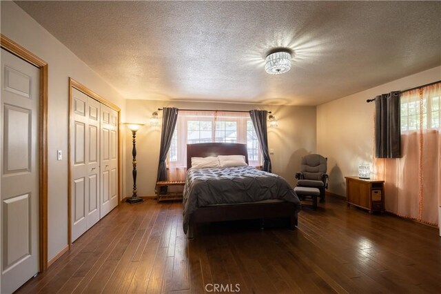 bedroom with baseboards, dark wood-style flooring, and a textured ceiling