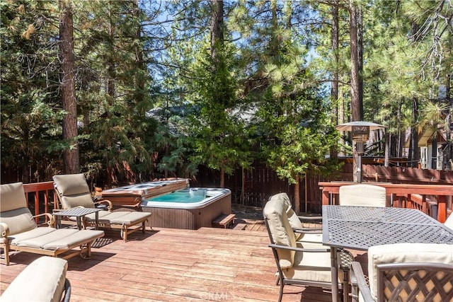 wooden deck with outdoor dining area, fence, and a hot tub