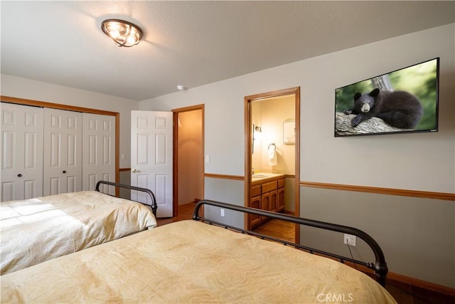 bedroom featuring ensuite bath, a closet, and baseboards