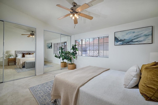 carpeted bedroom featuring a ceiling fan, two closets, and lofted ceiling
