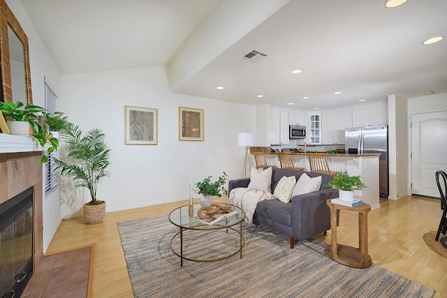 living room featuring light wood finished floors, recessed lighting, baseboards, a tile fireplace, and visible vents
