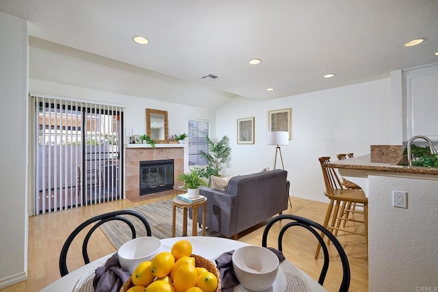 living room with visible vents, light wood-style floors, baseboards, recessed lighting, and a tiled fireplace