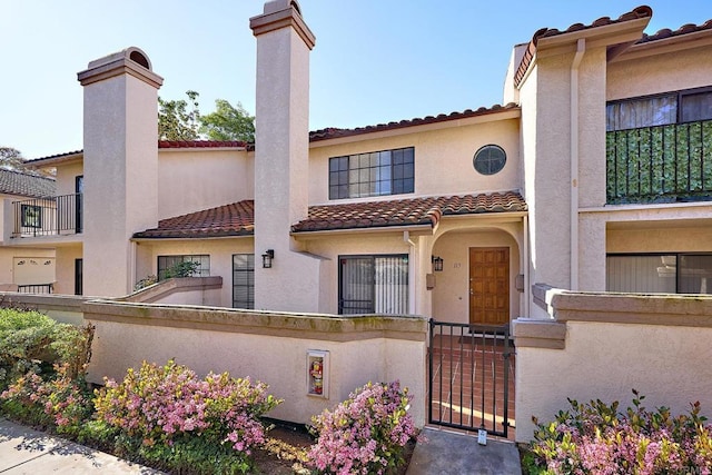 mediterranean / spanish-style home with a gate, a fenced front yard, stucco siding, and a tile roof