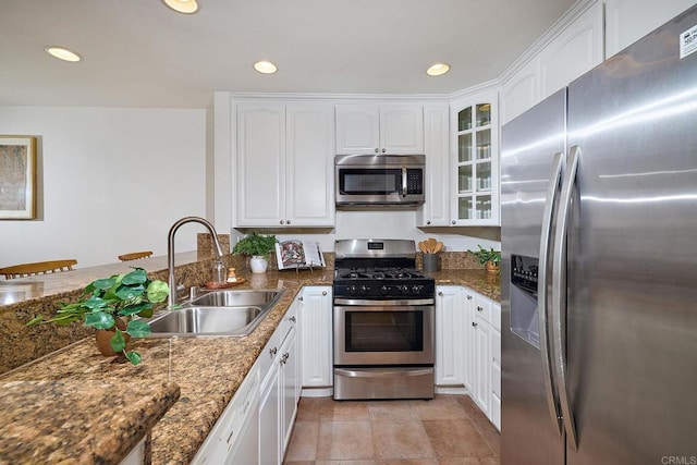kitchen with a sink, stainless steel appliances, recessed lighting, white cabinetry, and glass insert cabinets