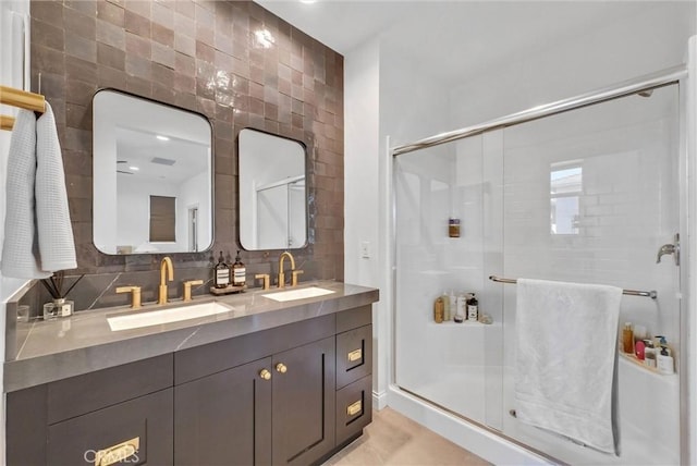 bathroom with a stall shower, double vanity, a sink, and tile walls