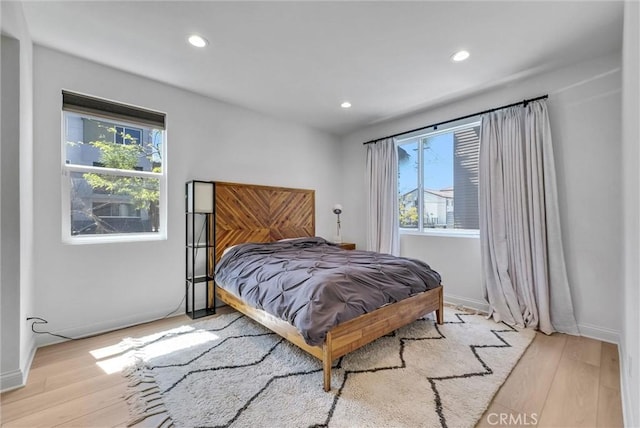 bedroom with recessed lighting, multiple windows, baseboards, and wood finished floors