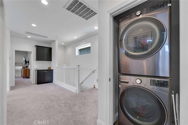 laundry room with light carpet, visible vents, stacked washer / drying machine, and laundry area