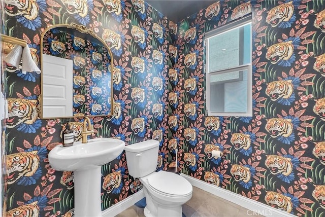 bathroom featuring toilet, baseboards, and wallpapered walls