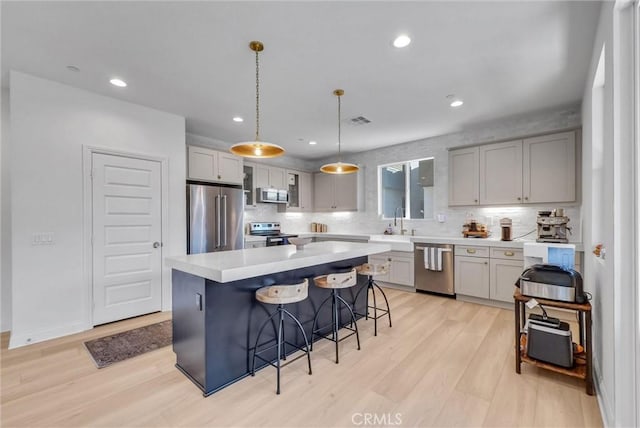 kitchen featuring light wood-type flooring, visible vents, appliances with stainless steel finishes, light countertops, and a breakfast bar area