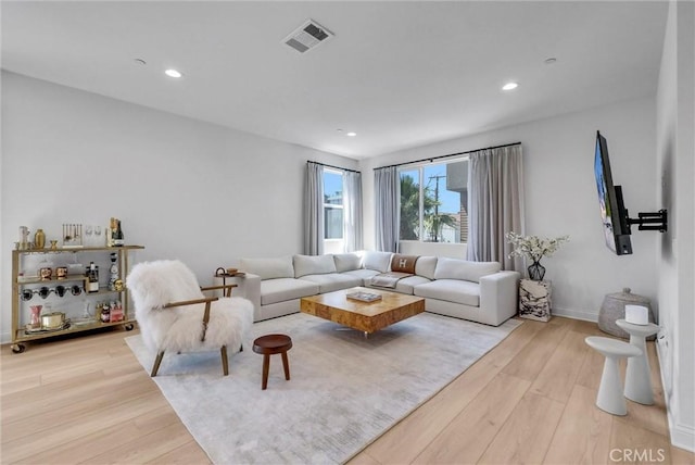 living room with visible vents, recessed lighting, and wood finished floors