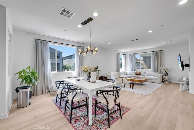 dining area featuring visible vents, light wood-type flooring, and a notable chandelier