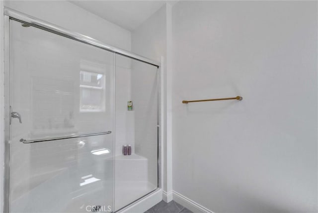 full bathroom with a shower stall and baseboards