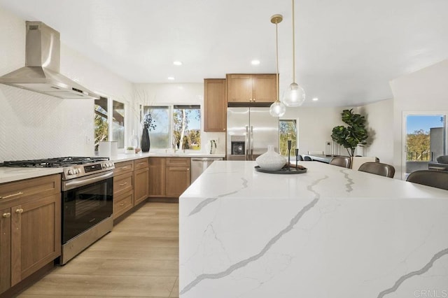 kitchen with tasteful backsplash, hanging light fixtures, ventilation hood, appliances with stainless steel finishes, and light wood-style flooring