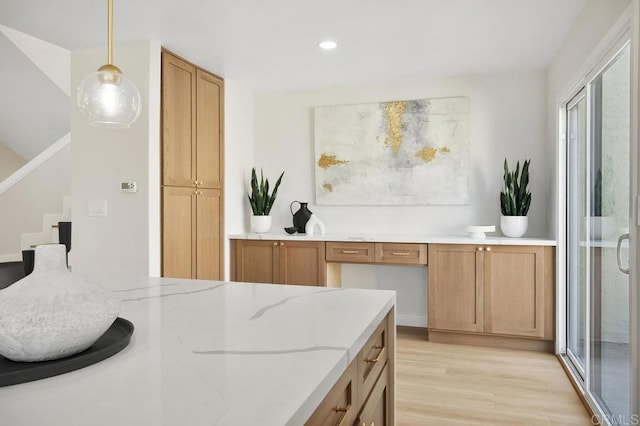 interior space featuring hanging light fixtures, brown cabinets, recessed lighting, light wood-style flooring, and light stone counters