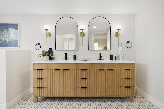 bathroom featuring a sink, double vanity, and baseboards