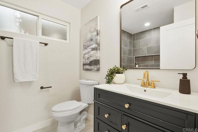 full bathroom featuring a tile shower, vanity, visible vents, toilet, and baseboards