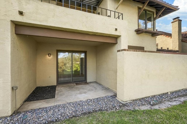 doorway to property featuring a patio, stucco siding, and a balcony