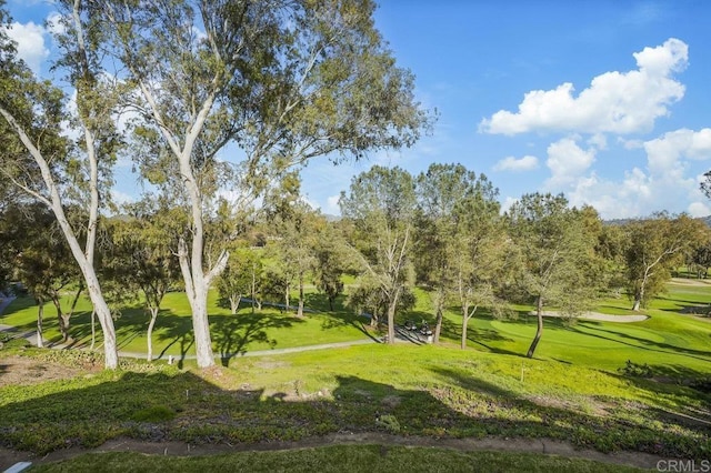 view of community featuring view of golf course and a yard