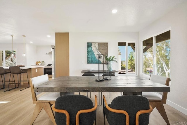 dining space with recessed lighting, plenty of natural light, light wood-style flooring, and baseboards