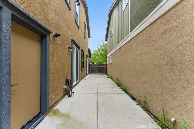 view of side of property featuring a patio, fence, and stucco siding