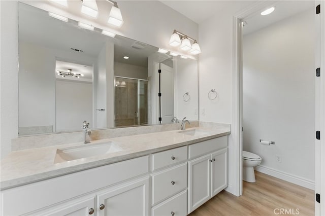 bathroom featuring toilet, a sink, a shower stall, and wood finished floors