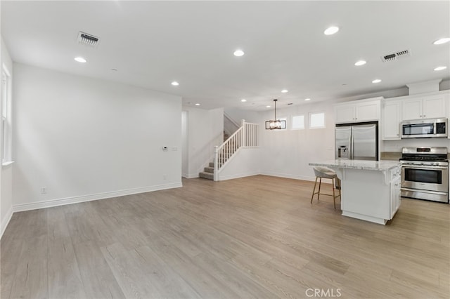 kitchen featuring a breakfast bar area, visible vents, stainless steel appliances, a center island, and recessed lighting