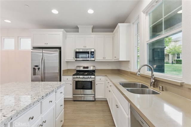 kitchen featuring stainless steel appliances, light wood-type flooring, white cabinets, and a sink
