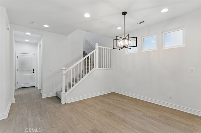 interior space featuring an inviting chandelier, visible vents, wood finished floors, and baseboards