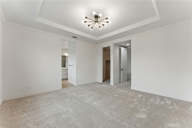 unfurnished room with crown molding, a raised ceiling, an inviting chandelier, and light colored carpet