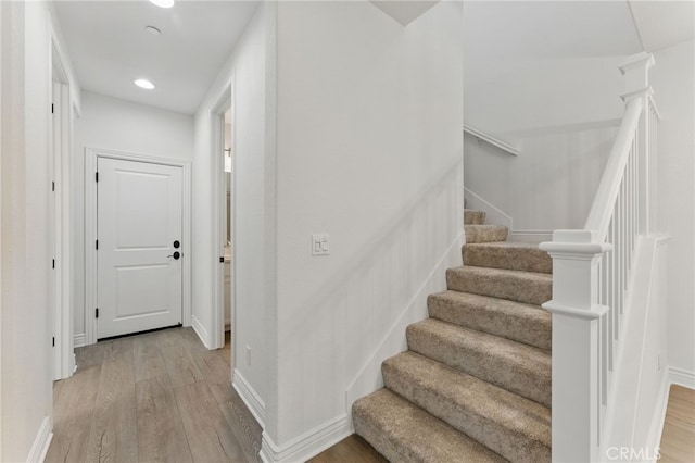 stairs with baseboards, recessed lighting, and wood finished floors