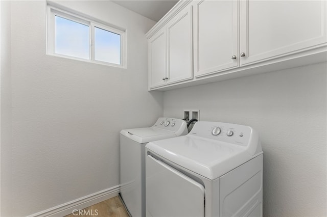 clothes washing area featuring cabinet space and washer and clothes dryer