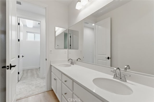 bathroom featuring double vanity, wood finished floors, visible vents, and a sink