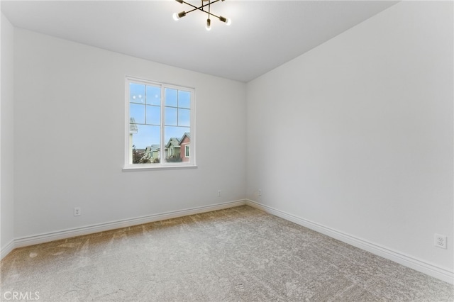 carpeted spare room with a notable chandelier and baseboards