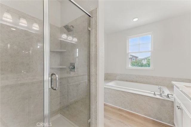 bathroom featuring a garden tub, a stall shower, wood finished floors, and vanity