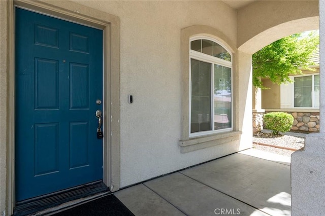 entrance to property featuring stucco siding and stone siding