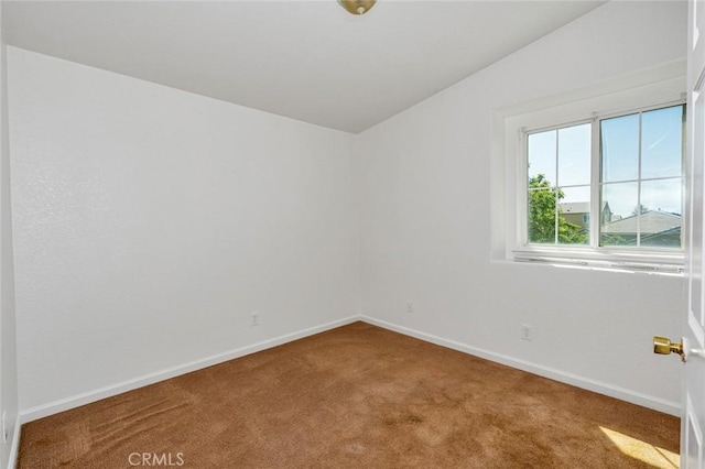 empty room featuring carpet floors, baseboards, and vaulted ceiling