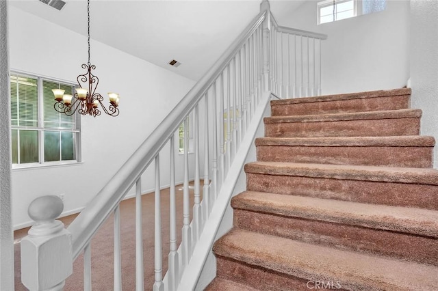 stairs featuring a chandelier, high vaulted ceiling, and carpet flooring